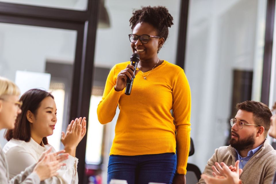 African American business woman talking on the microphone to her colleagues