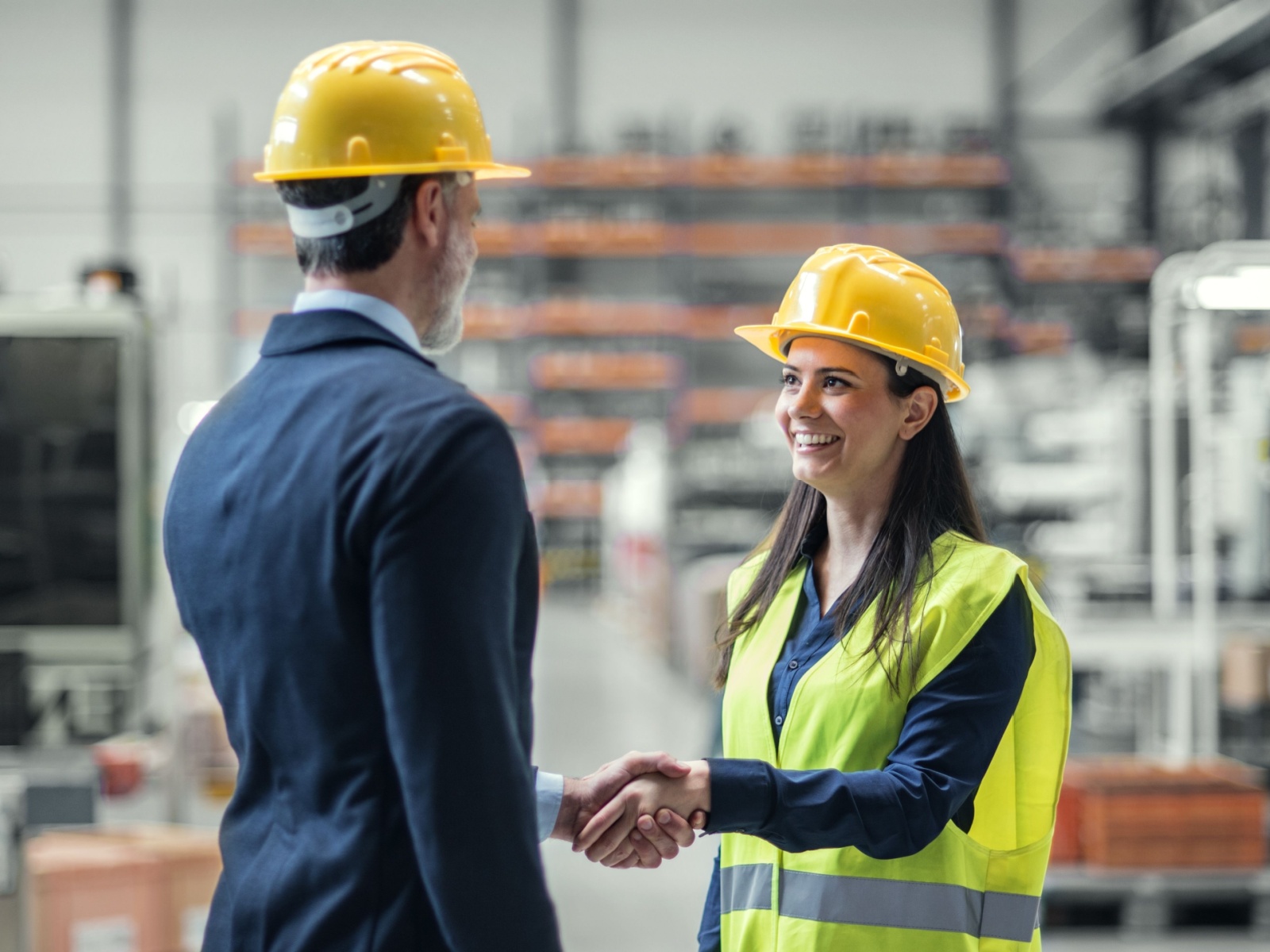 A woman shaking a man's hand and smiling in a warehouse