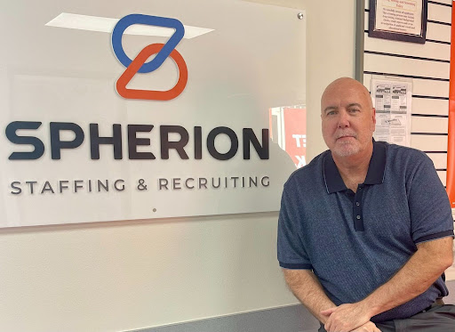 Greg Forrest next to a Spherion sign