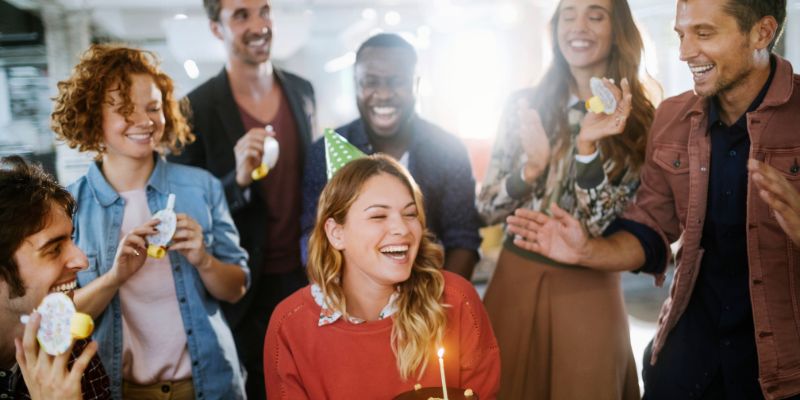 A group of colleagues smiling and laughing as the celebrate a birthday together