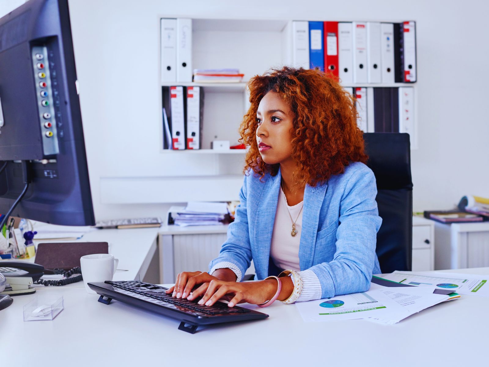 An African-American woman working on a computer in an office setting