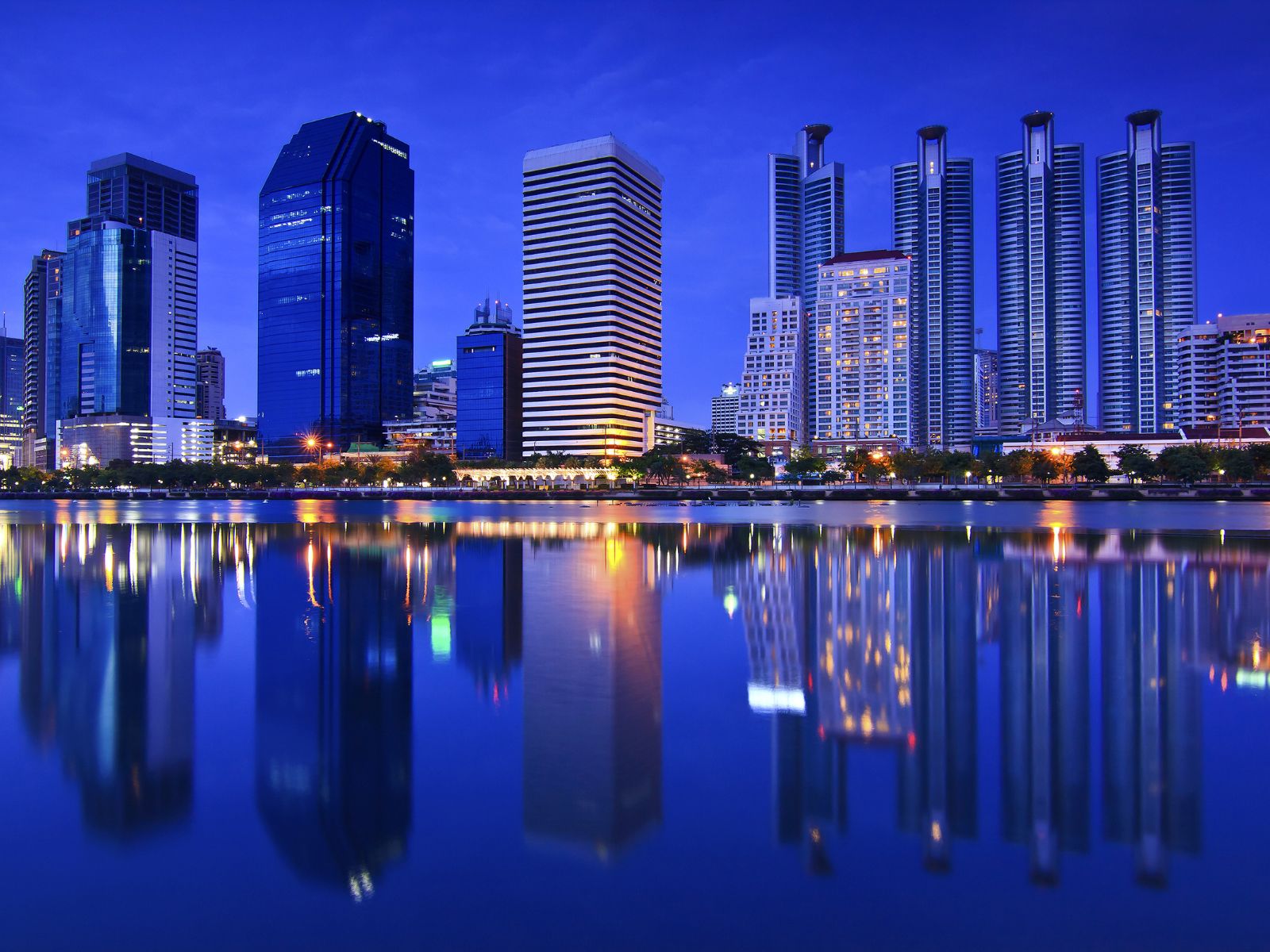 A city skyline at night reflected in the water