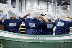 Four women on-premise workers pointing to the backs of their uniforms