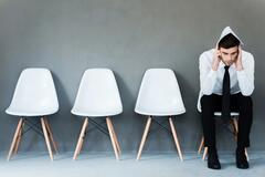 Man waiting for interview with resume on head