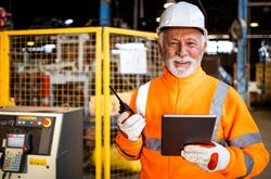 Workplace productivity is possible with a plan for balancing tasks and mental breaks. Older man in orange safety vest smiling in a factory setting