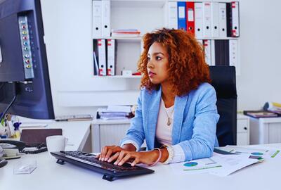 An African-American woman working on a computer in an office setting